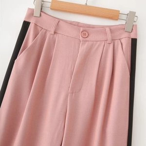 Detail of pink leisure trousers with black side stripes and resin button closure