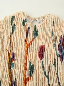 Detailed view of floral cotton linen dress with pleated texture and round cutout neckline