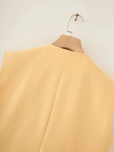 Detail of ginger yellow cotton vest texture and sewing craft on wooden hanger