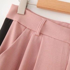 Detail of pink and black patchwork twill trousers with pleated waist and side stripes