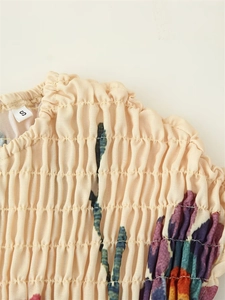Detailed view of cream floral cotton-linen dress featuring smocked bodice and size S label