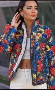 Detail view of quilted floral jacket with high collar and large pockets on dark blue base