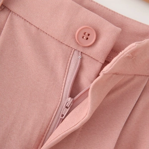 Close-up of light pink twill fabric with matching resin button and zipper detail