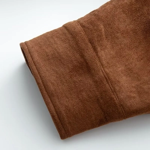 Close-up of high-quality stitching and soft brown suede texture on a bomber jacket