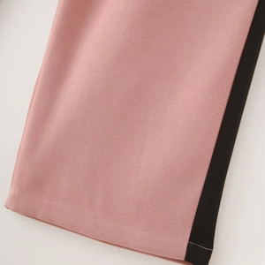 Detailed close-up of pink-purple blazer fabric with black contrast side trim and stitching