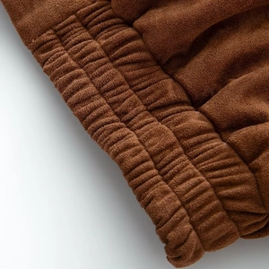 Detailed close-up of brown faux suede bomber jacket with elastic ribbed cuff texture