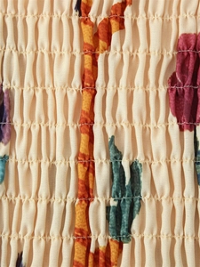 Detail of smocking texture and vibrant floral print on bohemian cotton blend dress
