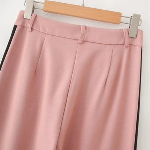 Detail of pink suit trousers with black side stripes and belt loops on a hanger