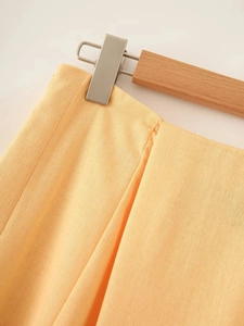 Detailed close-up of apricot linen-textured skirt waist with uniform stitching and wood hanger