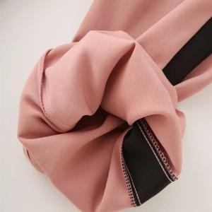 Detail shot of pink knit fabric with black contrast trim and professional stitching