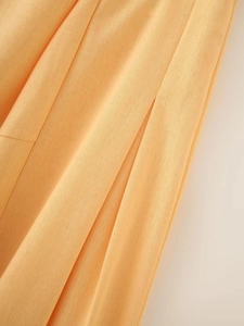 Detailed close-up showing the linen texture and stitch detail of the apricot skirt