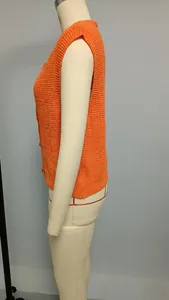 Close-up of orange knitted vest with chunky texture and animal-shaped buttons