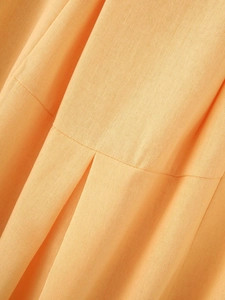 Close-up of textured linen fabric with fine seam stitching on orange-yellow skirt