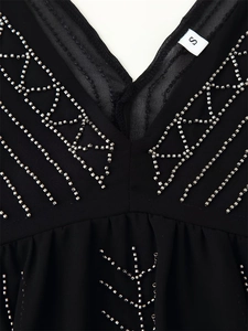 Detail of silver beaded geometric embroidery on a black V-neck top with S size label
