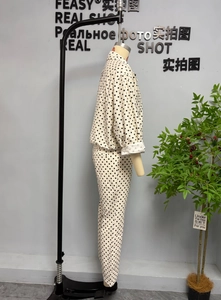 Detailed side view of white polka dot jacket and pants set on a mannequin