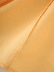 Close-up of light orange cotton-linen fabric with detailed plain weave and stitching