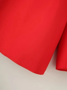 Detailed close-up of vibrant red blazer fabric with precise stitching and smooth texture
