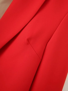 Close-up of bright red blazer showing textured twill fabric and side pocket stitching