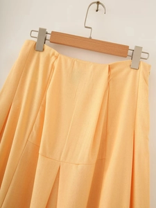 Detail of light orange pleated cotton linen skirt with natural fabric texture and waist folds