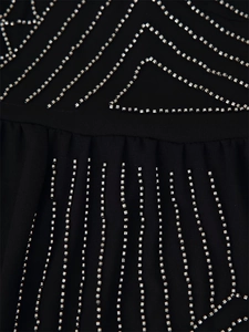 Close-up of black pleated top with intricate silver beaded geometric embroidery details