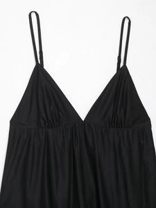 Detail of adjustable thin straps and delicate pleated V-neckline on a black midi dress