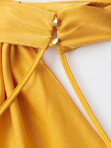 Detail of ginger satin dress featuring golden metal buttons and delicate ribbon neck tie