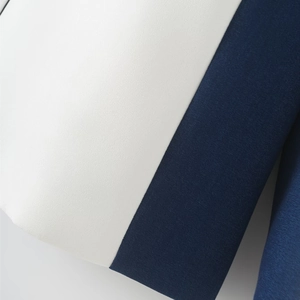 Close-up of contrast color patchwork details on a white and navy blue minimalist suit