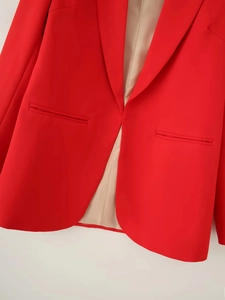 Detail of red blazer showing classic lapel collar and seamless front pocket design