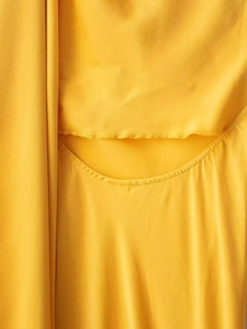 Detail of crescent cutout design on a slim yellow dress with fine matte texture
