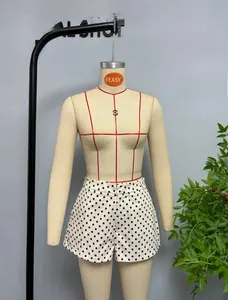 Detail view of high-waisted white shorts with black polka dots on a mannequin display