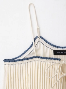 Detail of pleated camisole featuring contrast navy ruffled trim and adjustable straps