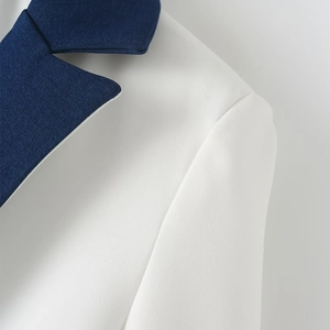 Detail of white blazer with navy contrast lapel showing high-quality twill fabric texture