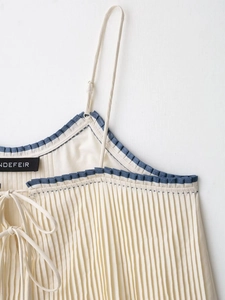 Detail of camisole top featuring blue ruffled trim and fine pleated fabric texture