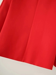 Detail of red blazer fabric showing vertical seam and smooth woven texture
