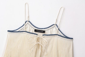 Close-up of pleated beige camisole featuring navy blue contrast trim and front bow detail