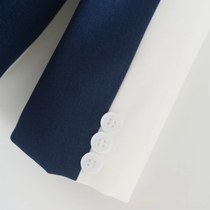 Detail of navy blue blazer sleeve featuring white contrast cuffs and three buttons