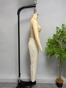 Detailed side view of white polka dot slim fit trousers displayed on a mannequin