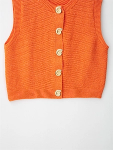 Detailed texture of orange knitted vest with artistic gold snail-shaped metal buttons