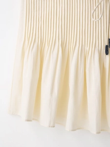 Close-up of pleated cream fabric with blue beaded drawstring tie detail