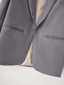 Detailed close-up of grey blazer showing welt pockets and smooth silky inner lining