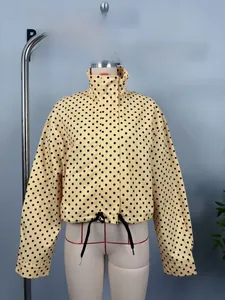 Close-up of yellow polka dot jacket showing stand collar and long sleeves detail