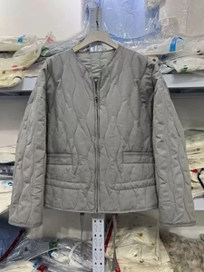 Detail of grey quilted jacket featuring unique wavy stitching and metallic zipper closure