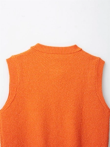 Detail of orange knitted vest showing premium honeycomb texture and ribbed neckline finish