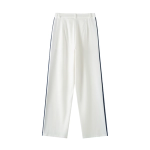 Detail of white wide-leg trousers featuring navy blue side stripes and pleat design