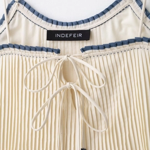 Chic off-white pleated tank top with blue contrast trim and a delicate bow tie