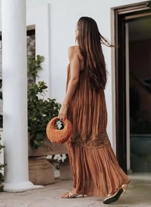 Detail of terracotta pleated dress with lace hem and woven bag for summer vacations