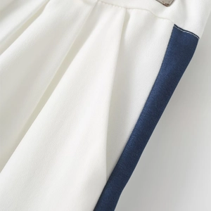 Detailed view of white tailored pants with navy side stripes and precise stitching