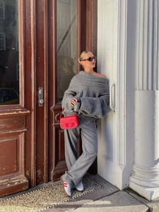 Detail of off-shoulder grey knit sweater paired with red leather bag and wide-leg trousers
