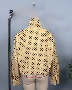 Rear view of yellow polka dot bomber jacket with stand collar and elastic hem details