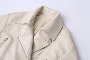 Close-up detail of cream faux leather moto jacket showing lapels and silver zippers
